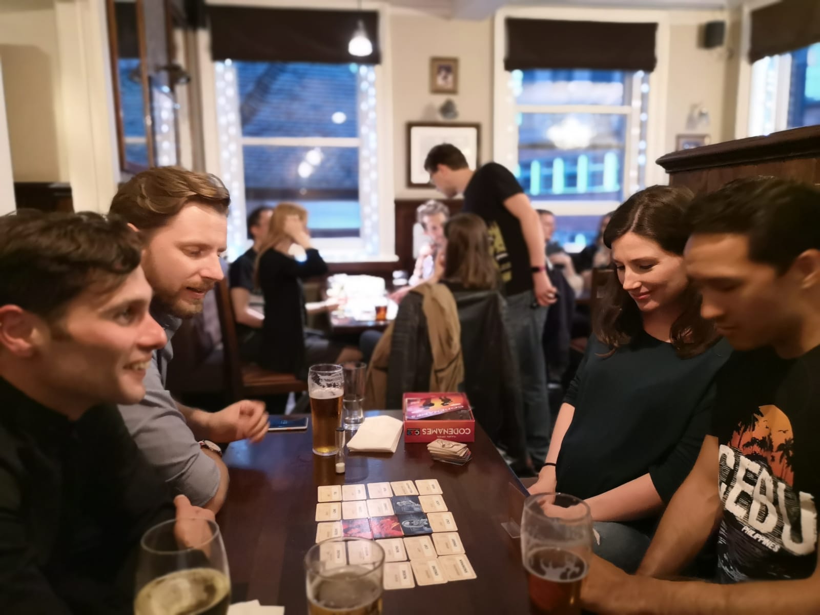 A friendly host teaching a board game to newcomers